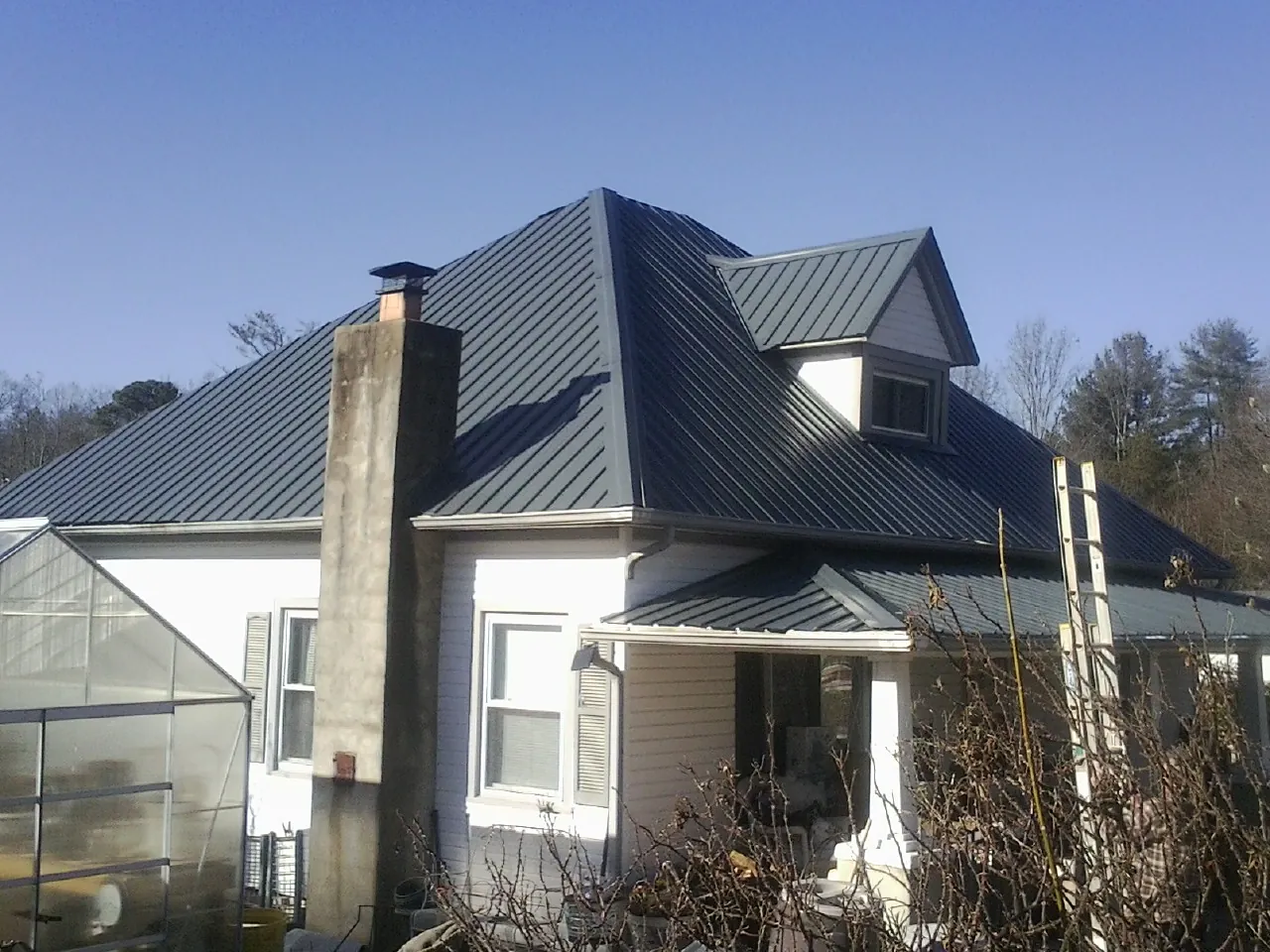 Dark blue standing seam metal roof on a white farmhouse with dormer — Slate & Tile Roof Repair by Roofing Brothers in Saint David