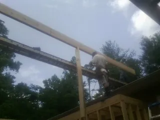 Carpenter setting a ridge beam over a new addition frame — Ice Dam Removal by Roofing Brothers in Saint David