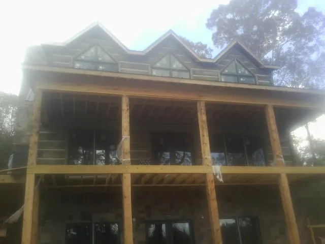Dormers and porch framing on a large log home under construction — Roof Coating work by our crew in Saint David