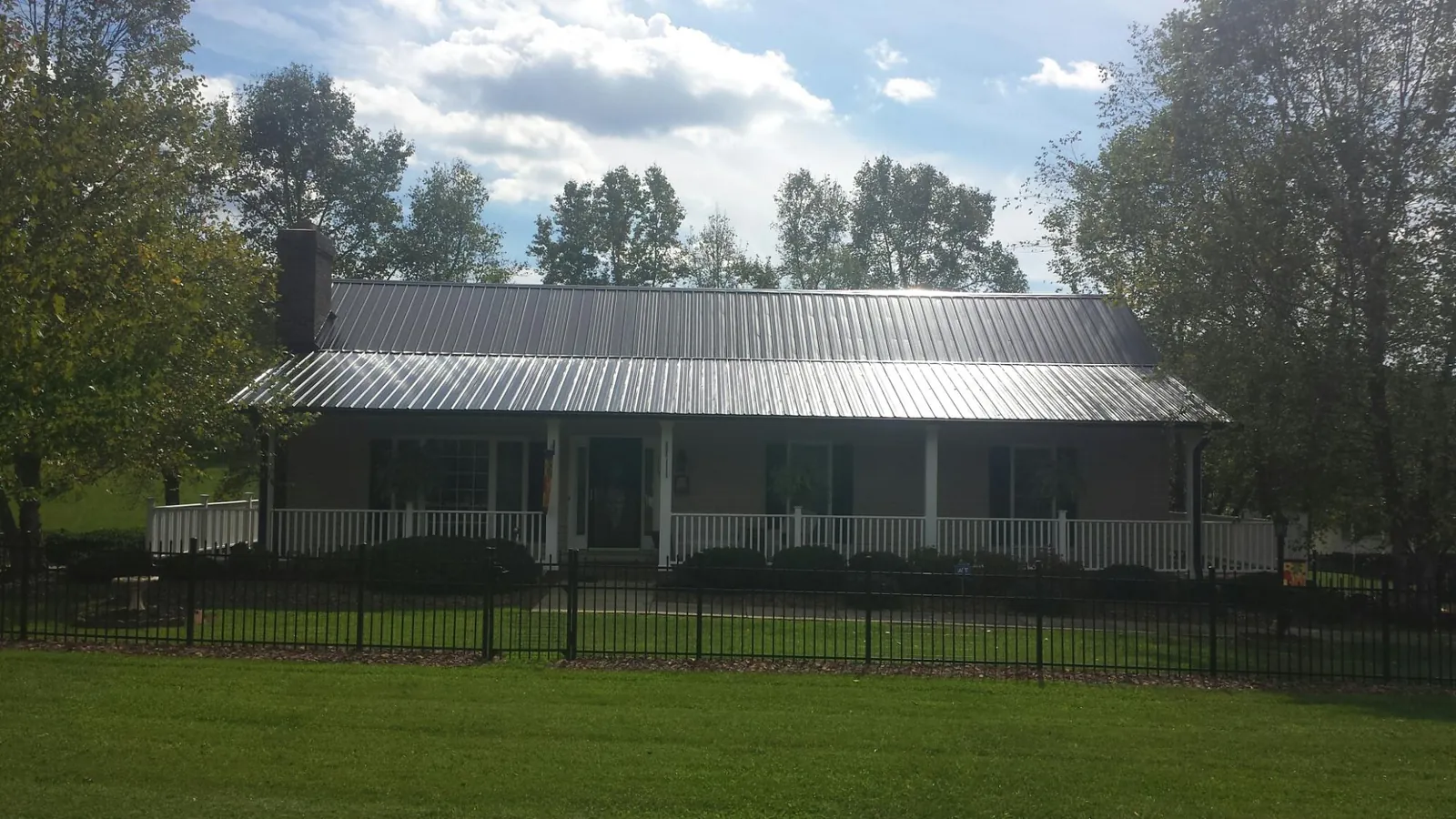 Gray metal roof on a brick ranch with a full width front porch — Gutter Guard Installation work by our crew in Saint David