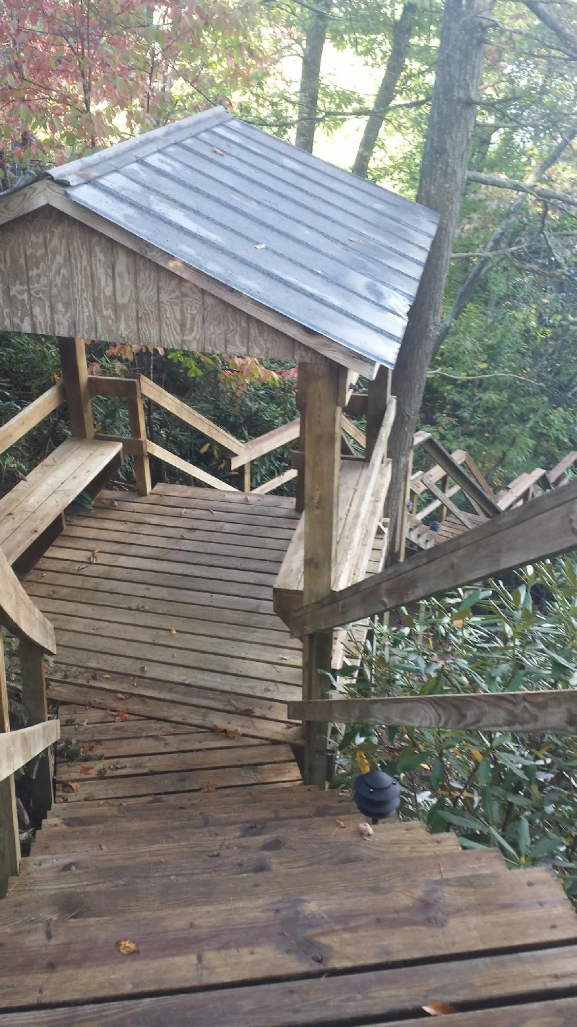 Metal roofed shelter over wooden steps on a wooded walkway — Skylight Repair & Installation work by our crew in Saint David
