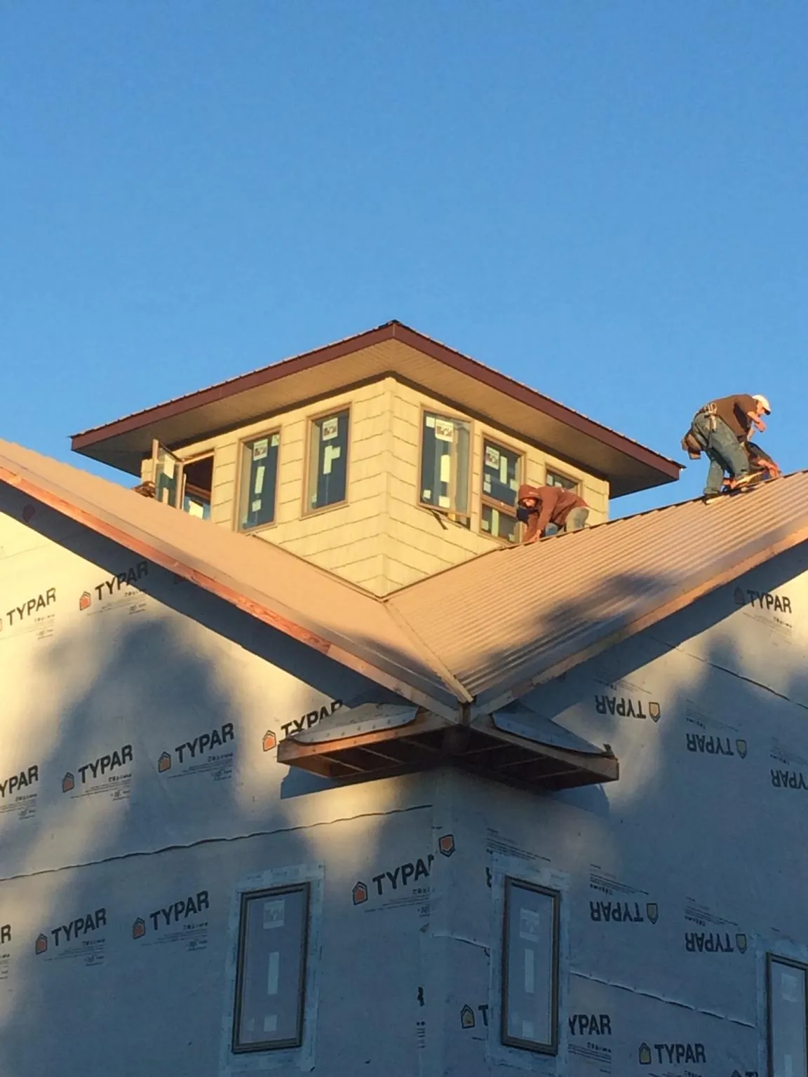 Roofers working around a rooftop cupola on a new metal roof at sunset — Roof Waterproofing in Saint David by Roofing Brothers